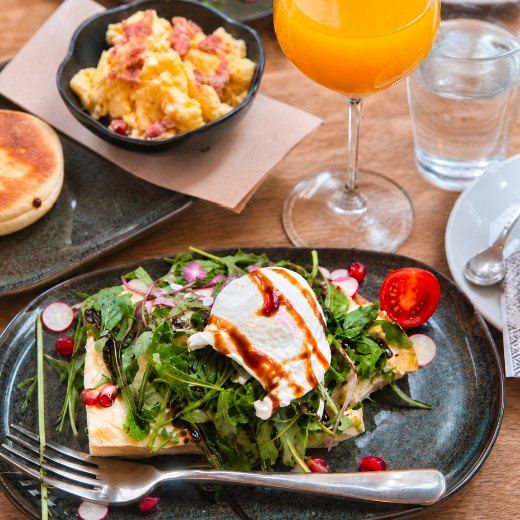 Une table du matin : œuf poché sur tartine, roquette et radis, œufs brouillés au bacon, jus d'orange pressé